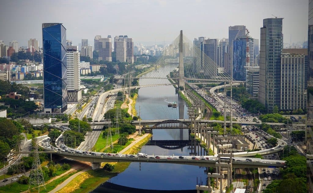 Amazing view of modern urban district in Sao Paolo with futuristic bridge and constructions over river during clear day