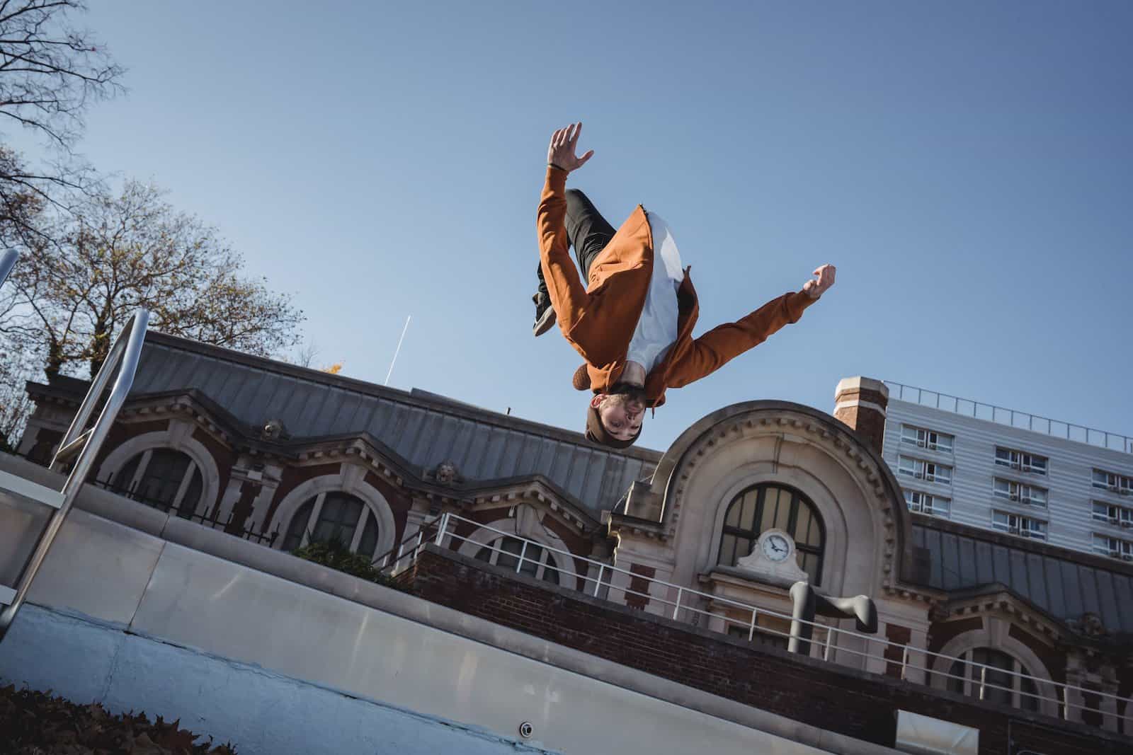 Les 10 sports extrêmes les plus dangereux au monde From below of sportsman jumping in air while demonstrating upside down trick during training against urban building